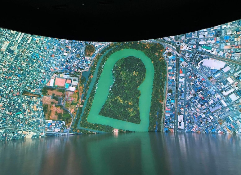 An aerial view of a city with a large body of water, a park with a distinctive shape, and densely packed buildings. 2
