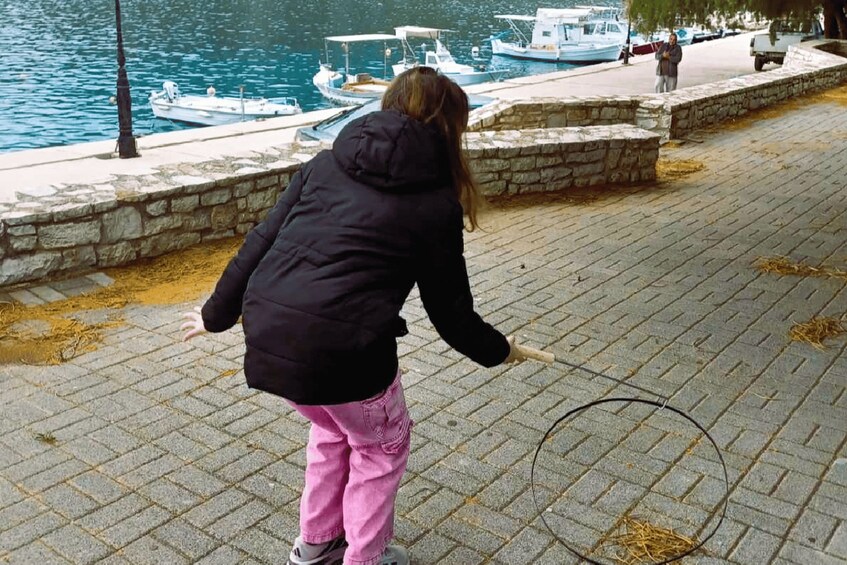 A person in a black jacket and pink pants near a waterfront with boats docked. 2