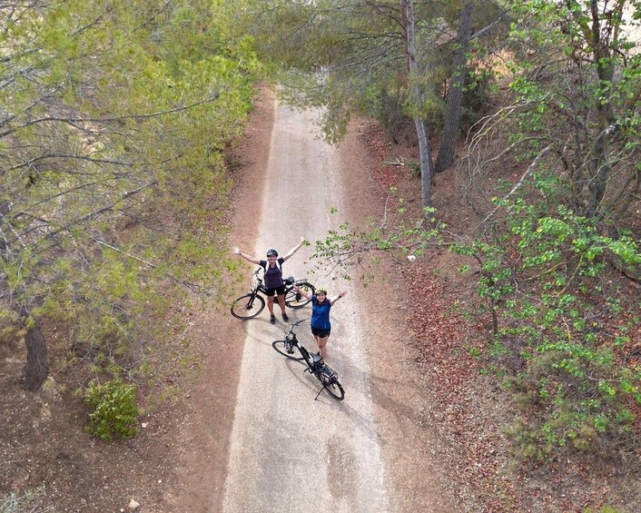 Two cyclists on a dirt path surrounded by trees. 5