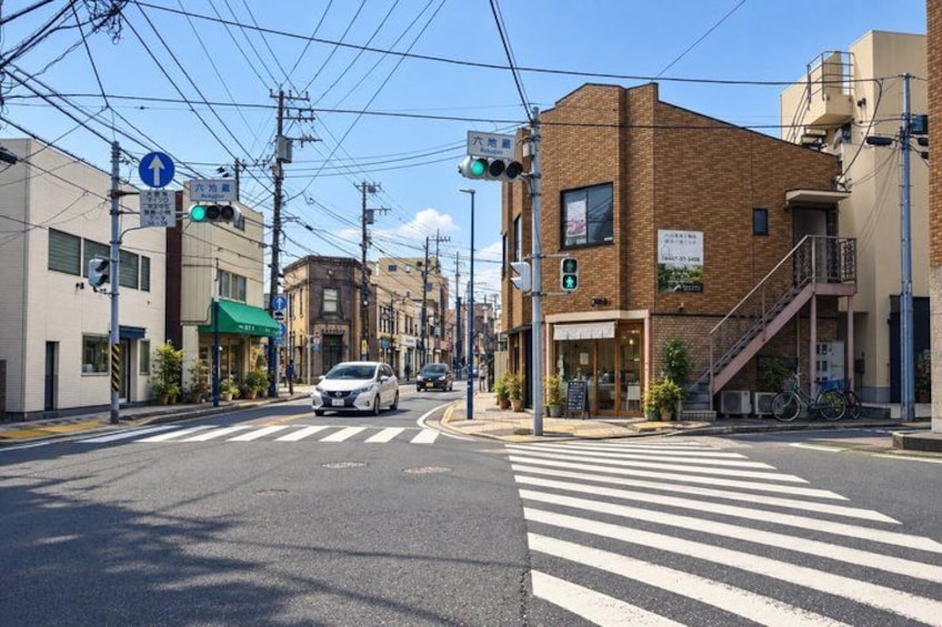 A crosswalk at an intersection with a white car, buildings, and a bicycle parked on the sidewalk. 3