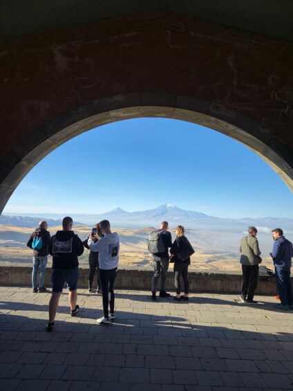 A group of people standing under an archway overlooking a mountainous landscape. 4