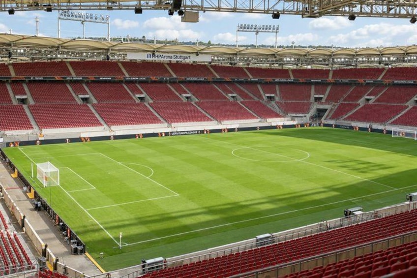 A large, empty stadium with a green field and red seating. 2