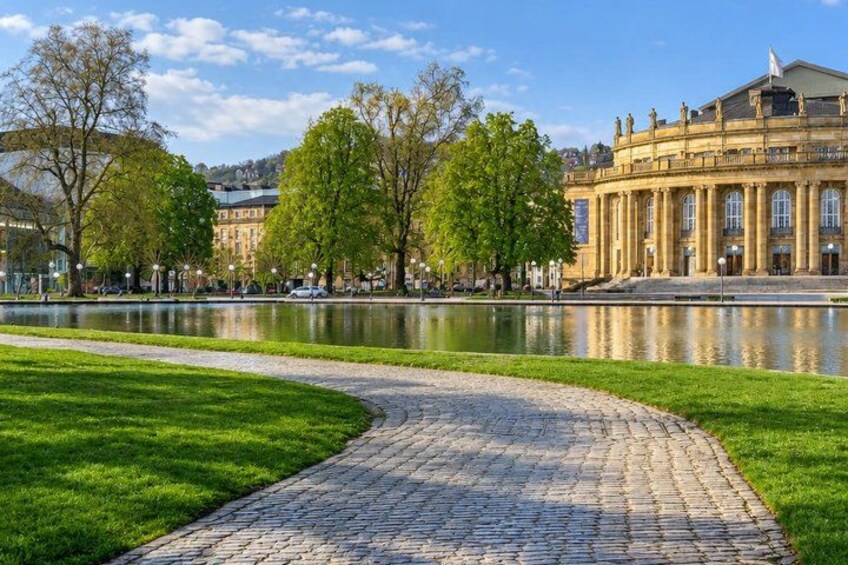 A cobblestone path, a body of water, and a classical building with columns. 5