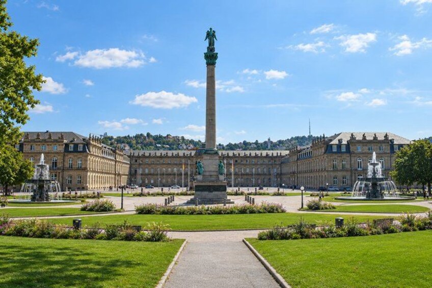 A large building with a central monument, surrounded by a well-maintained garden and a clear sky. 3