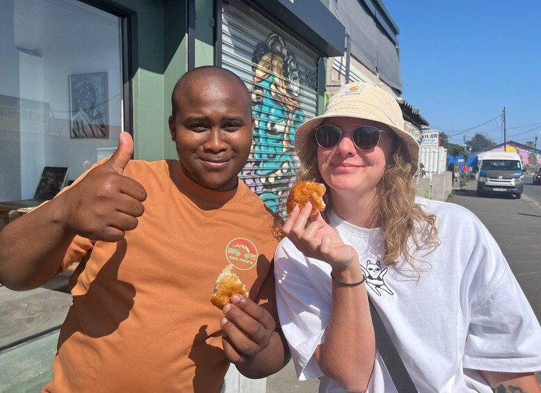 Two people giving thumbs up and holding food items. 5