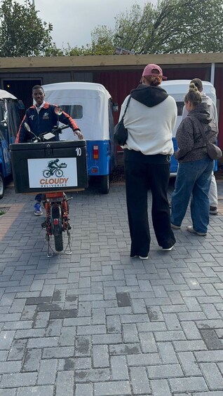 A delivery person on a bicycle with a box labeled 'CLOUDY DELIVERIES' in front of a white van. 4