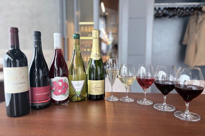 A selection of wine bottles and glasses on a wooden table. 5
