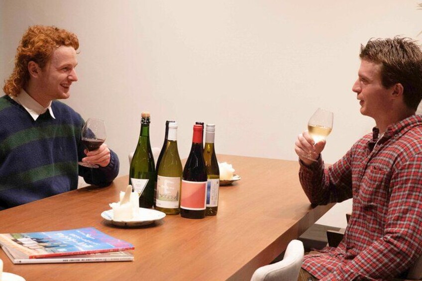 Two people sitting at a table with wine bottles and glasses. 3