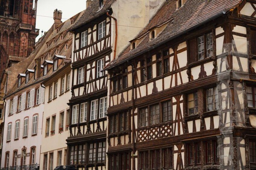 A row of half-timbered buildings with intricate wooden frameworks and white plaster infill. 3