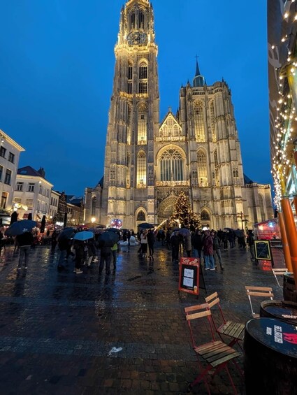 A historic cathedral with a tall bell tower, a decorated Christmas tree, and a crowd of people. 4
