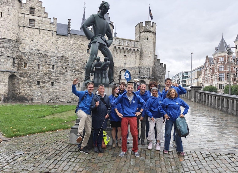 A group of people posing in front of a historic stone castle with a statue. 1