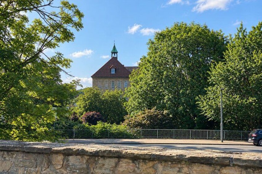 A stone wall, a metal fence, and a building with a green roof. 5