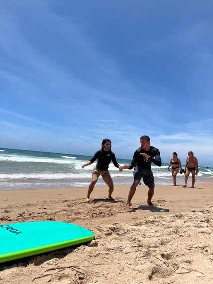 Una playa con gente practicando actividades acuáticas, una tabla de surf y olas del océano. 3