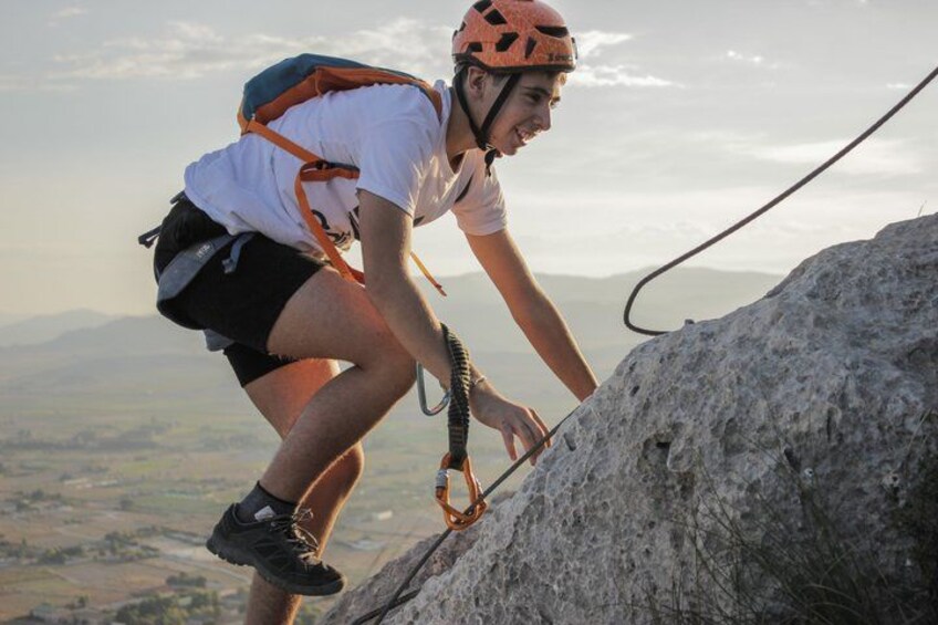 A person climbing a rock with a helmet and harness. 2