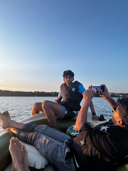 Three people on a boat with a calm body of water and a clear sky in the background. 3