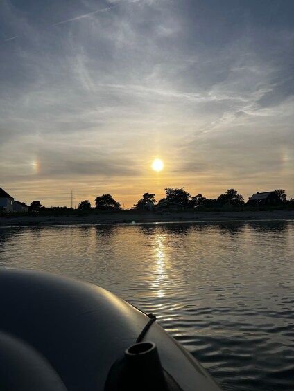 A sunset over a calm body of water with a boat in the foreground. 4