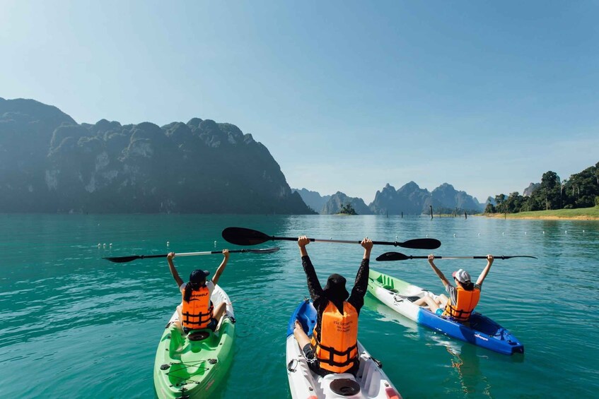 Three kayakers on a calm lake with mountainous scenery in the background. 2