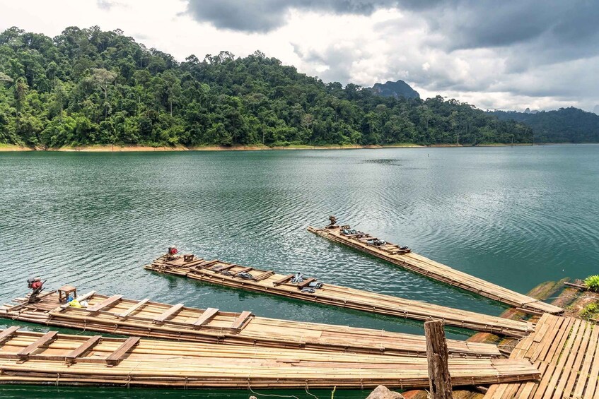 A calm lake with bamboo rafts and a forested mountain in the background. 5