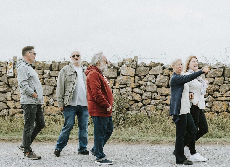 A group of people walking along a path with a stone wall in the background. 4