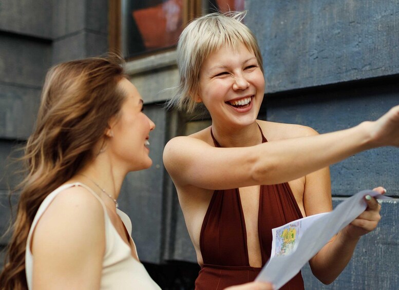 Two people, one holding a map, standing in front of a building with a window. 2