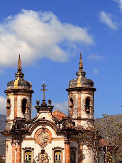 A historic church with two bell towers, a cross on the central tower, and a mountain in the background. 5