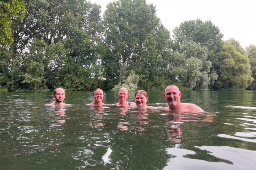 A group of people swimming in a river surrounded by dense trees. 2