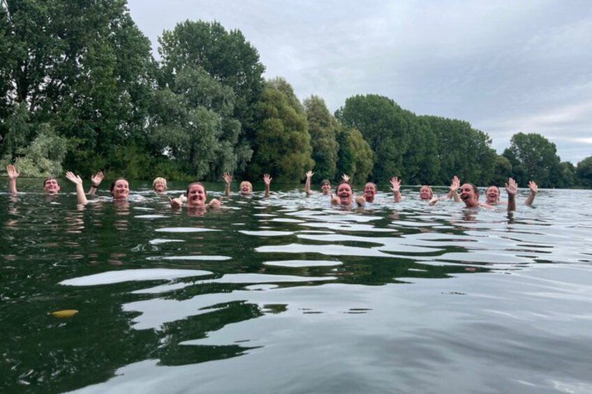 A group of people swimming in a lake surrounded by trees. 5