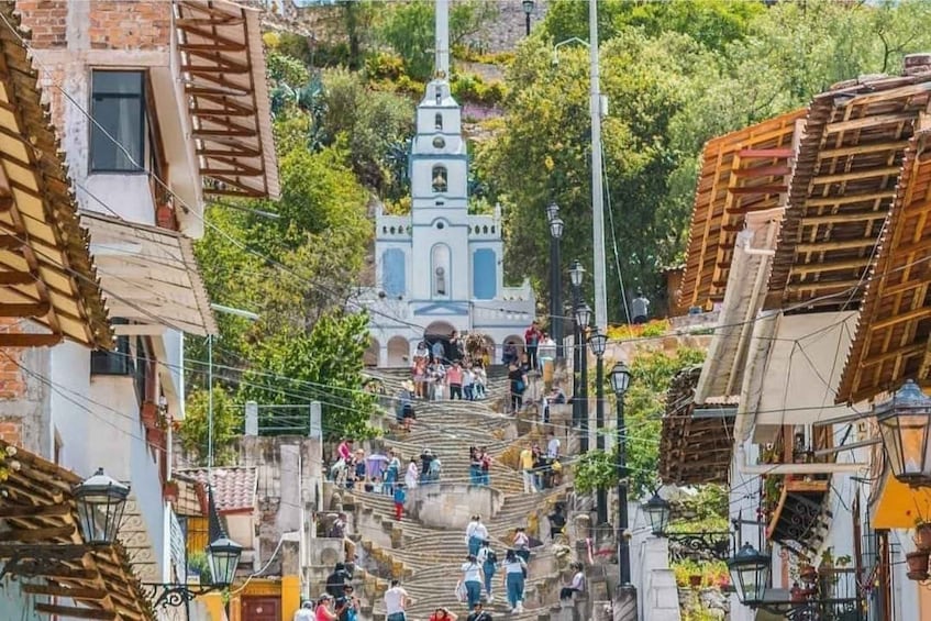A town with a prominent church at the top of a steep hill, surrounded by residential buildings. 2