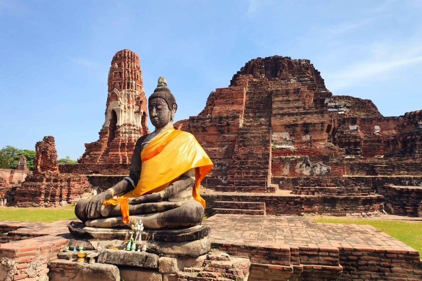 Istuva Buddha-patsas temppelialueella, jossa on vanhoja tiilirakennuksia. 3