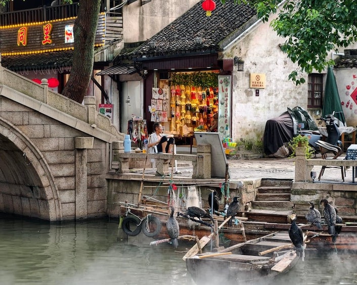 Un pintoresco pueblo acuático tradicional chino con puentes de piedra, barcas de madera y una tienda con decoraciones coloridas. 2