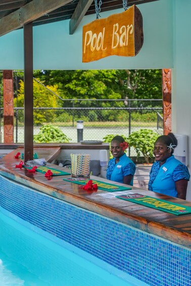 Un bar au bord de la piscine, avec une enseigne, deux personnes et une piscine. 3