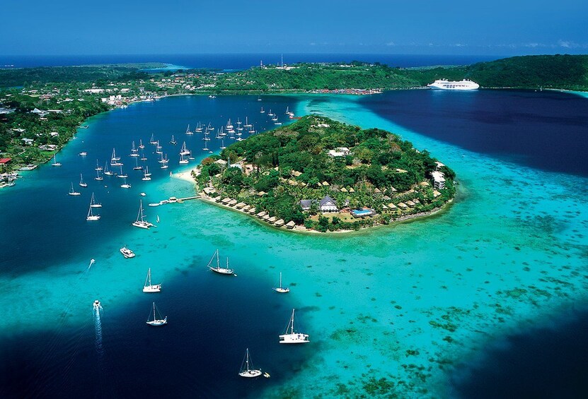 Une île entourée d’eaux turquoise, où de nombreux voiliers sont amarrés tout autour. 1