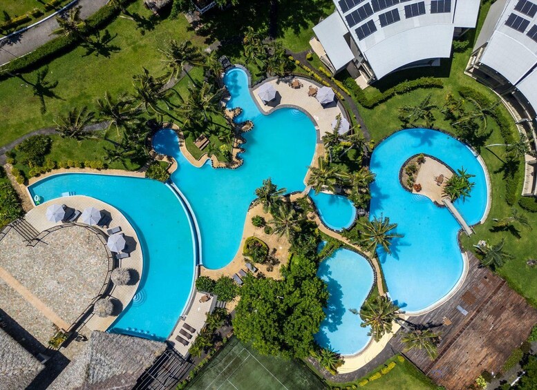 Un grand complexe hôtelier doté de plusieurs piscines, de palmiers et d’espaces de détente. 5