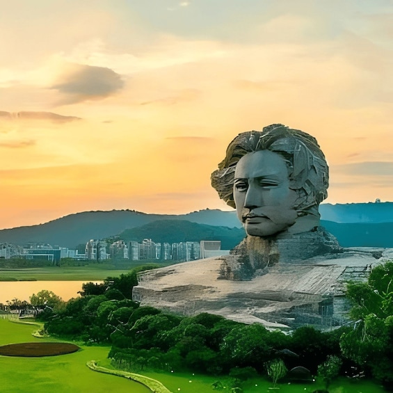 Una estatua grande de un hombre con barba, con un cielo de atardecer como fondo, y una ciudad y colinas a lo lejos. 3
