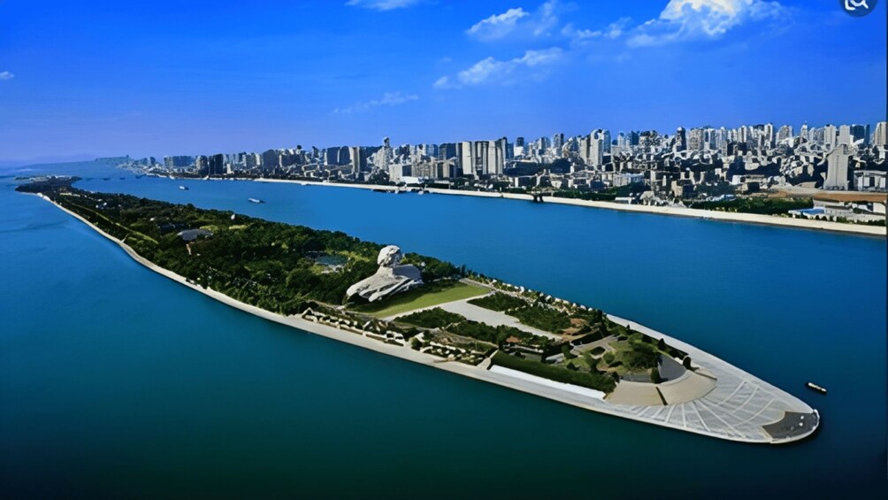 Un paisaje urbano costero con una isla alargada destacada, que presenta un gran monumento blanco, abundante vegetación y un parque bien cuidado. 5