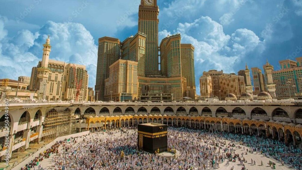 En stor menneskemængde har samlet sig omkring Kaaba i Mekka, mens moderne skyskrabere rejser sig i baggrunden. 1