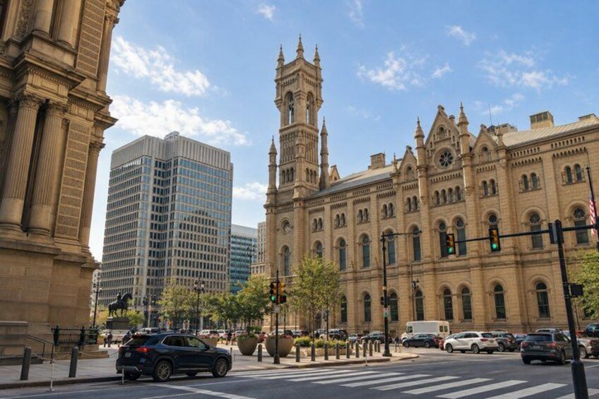 A historic building with a clock tower, a modern skyscraper, and a crosswalk with cars. 3