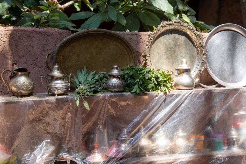 A collection of antique metalware, including a pitcher, a jug, and a plate, displayed on a table with a protective covering. 5