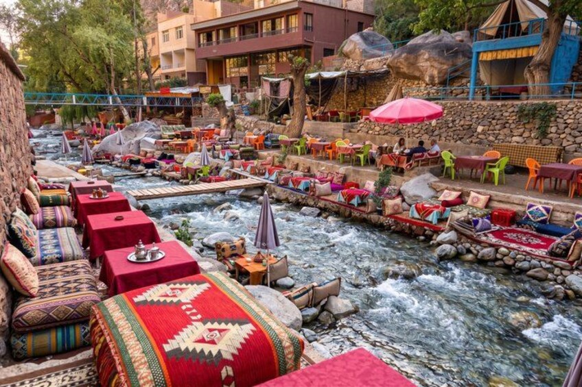 A riverside restaurant with outdoor seating, tables, and umbrellas. 5