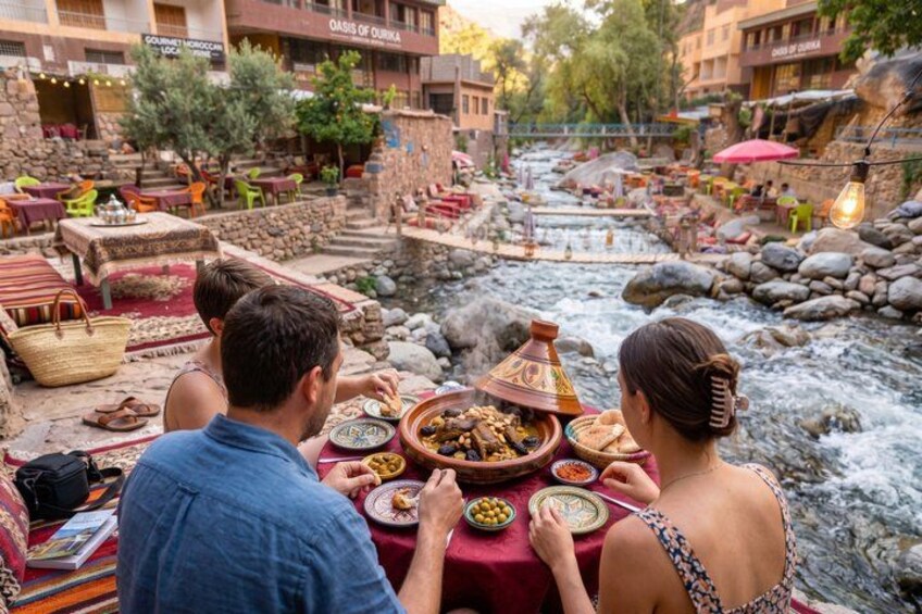A dining area with a river, stone tables, and traditional Moroccan dishes. 4