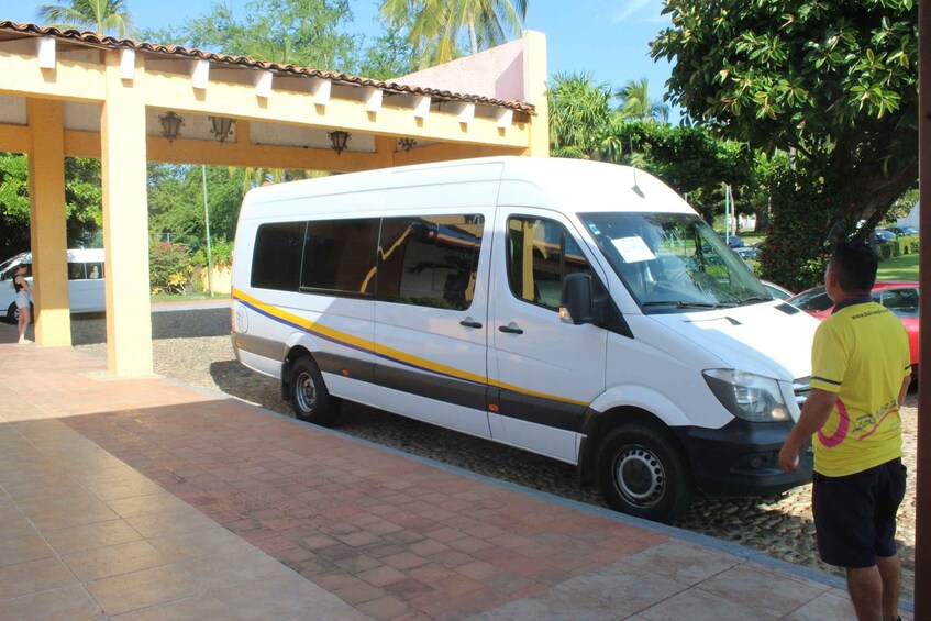 Una camioneta blanca estacionada bajo un área techada con piso de baldosas. 5