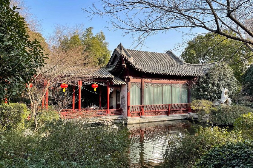 A traditional Chinese pavilion with a tiled roof, red pillars, and a small pond with a statue. 3