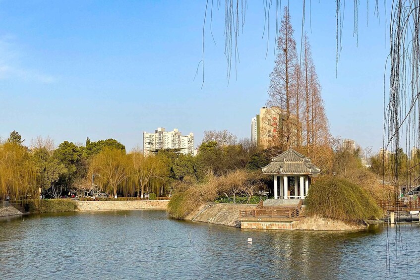 A tranquil park with a pond, a gazebo, and a backdrop of modern buildings. 2