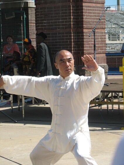 A person in traditional martial arts attire performing a stance with a staff. 2