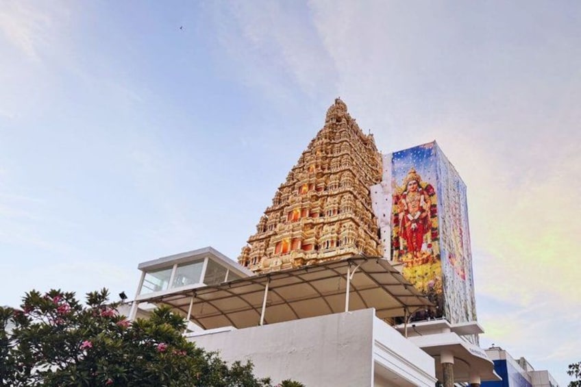 A temple with intricate architecture, a large mural, and a modern building in the foreground. 1