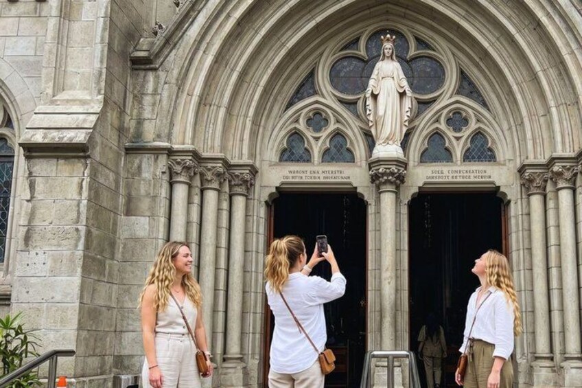 A historic building with a statue and two people taking a photo. 2