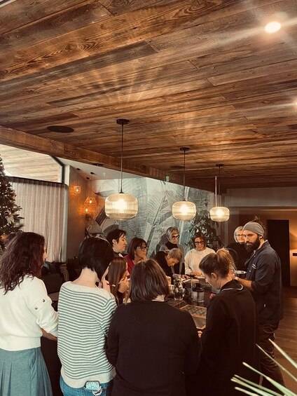 Un grupo de personas reunidas alrededor de una mesa en una habitación con techos de madera y lámparas colgantes. 2