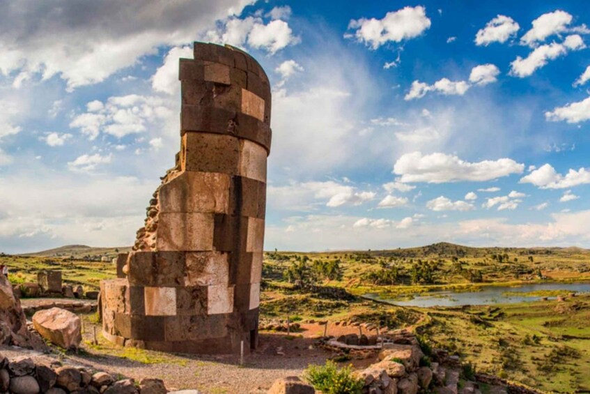 A stone structure with a curved top, surrounded by a rural landscape with hills and a river. 1