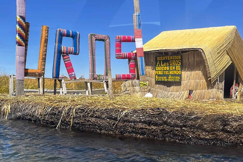 A traditional structure with colorful woven poles, a thatched roof, and a sign in Spanish. 3