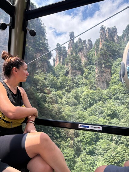 Una persona sentada en un teleférico, con un paisaje montañoso al fondo. 2